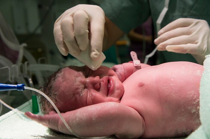 Newborn baby crying in a hospital crib