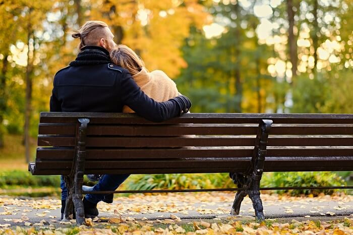 Image of a couple sitting back to back on a park bench, showing lack of communication in their relationship.